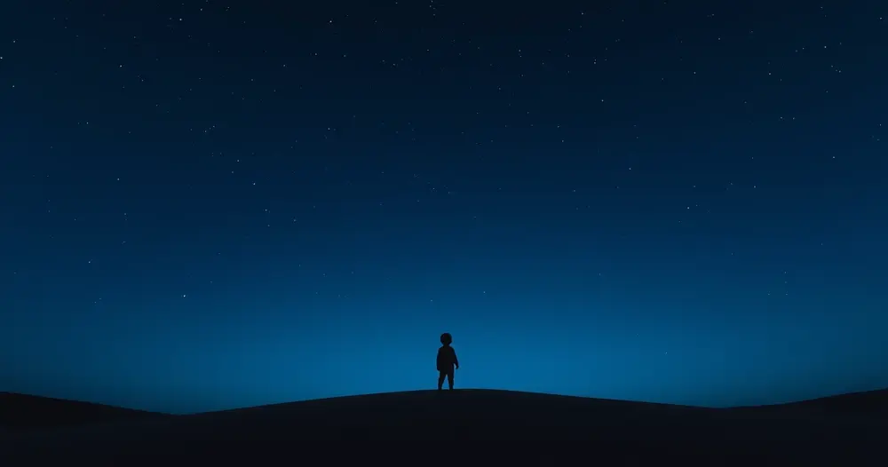 Silhueta de uma criança sozinha sobre uma duna de areia sob céu estrelado de tom azul profundo