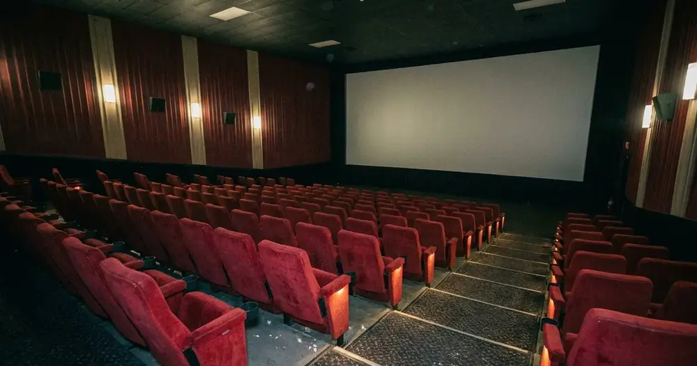 sala de cinema vazia com poltronas vermelhas diante de tela branca